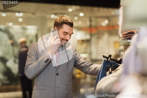 Image of happy man calling on smartphone at clothing store