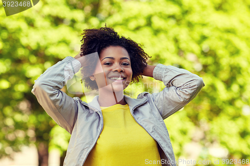 Image of happy african american young woman in summer park