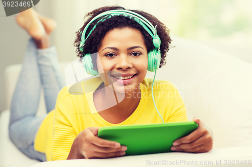 Image of happy african woman with tablet pc and headphones