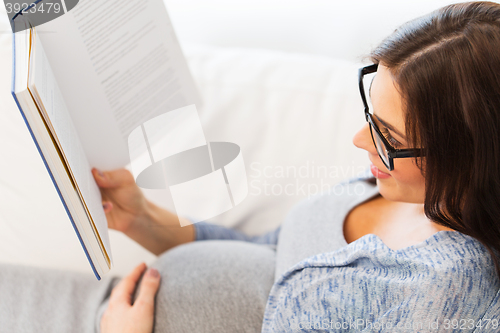Image of close up of pregnant woman reading book at home
