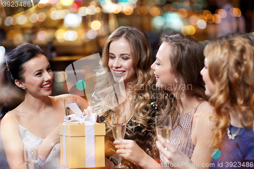 Image of happy women with champagne and gift at night club