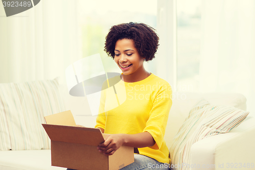 Image of happy african young woman with parcel box at home