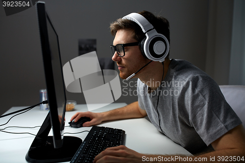 Image of man in headset playing computer video game at home