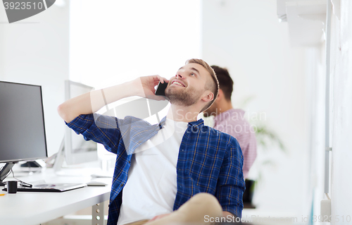 Image of happy creative man calling on cellphone at office
