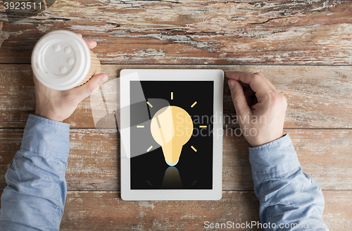 Image of close up of hands with ligting bulb on tablet pc