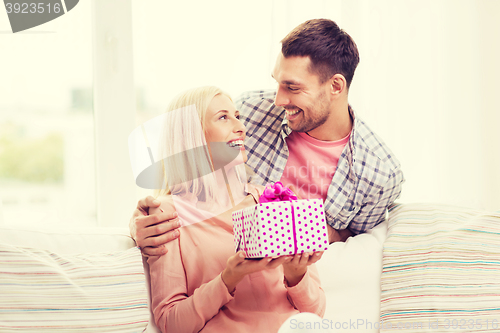 Image of happy man giving woman gift box at home