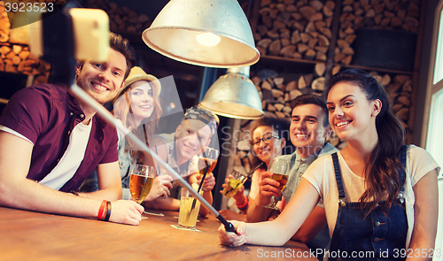 Image of friends with smartphone on selfie stick at bar