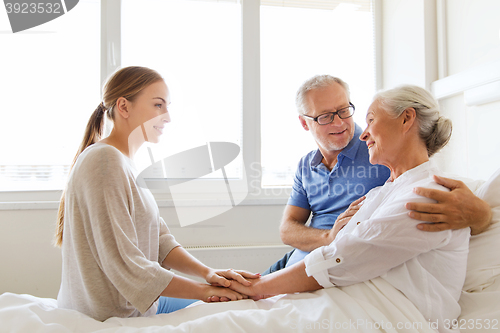 Image of happy family visiting senior woman at hospital