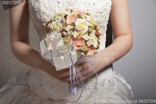 Image of Bride is holing wedding flowers. Focus on flowers