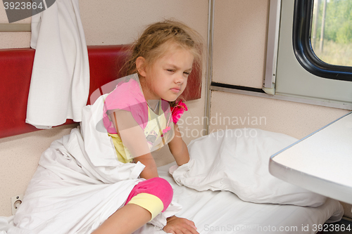 Image of The girl on the train sleepily gets out of bed on the lower place in the second-class compartment wagon