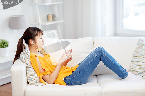 Image of happy asian woman with smartphone and earphones