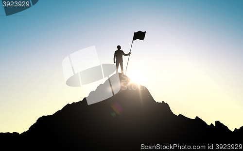 Image of silhouette of businessman with flag on mountain