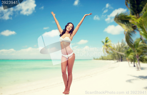 Image of happy woman in bikini swimsuit dancing on beach