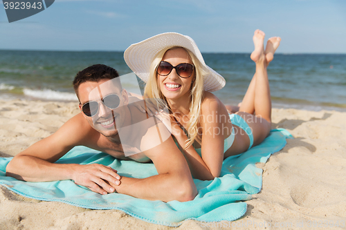 Image of happy couple in swimwear lying on summer beach