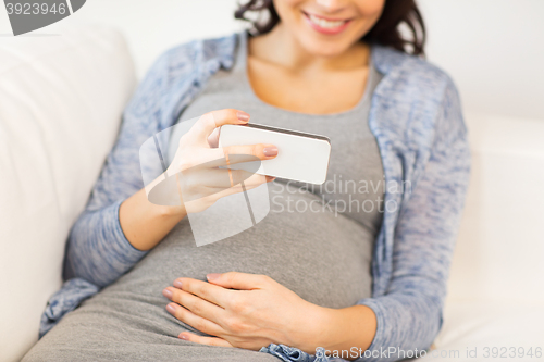 Image of close up of pregnant woman with smartphone at home