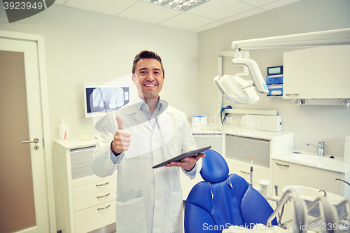 Image of happy dentist showing thumbs up with tablet pc