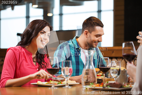 Image of happy couple with friends eating at restaurant