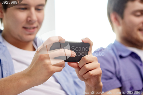 Image of close up of happy friends with smartphones at home