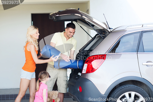 Image of happy family packing things to car at home parking