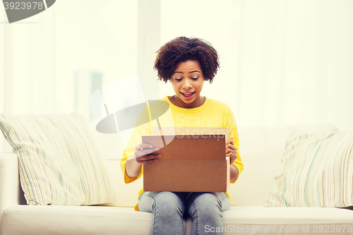 Image of happy african young woman with parcel box at home