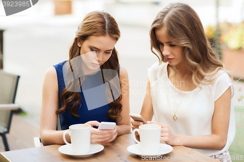 Image of women with smartphones and coffee at outdoor cafe