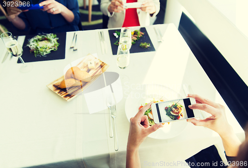 Image of close up of women picturing food by smartphones