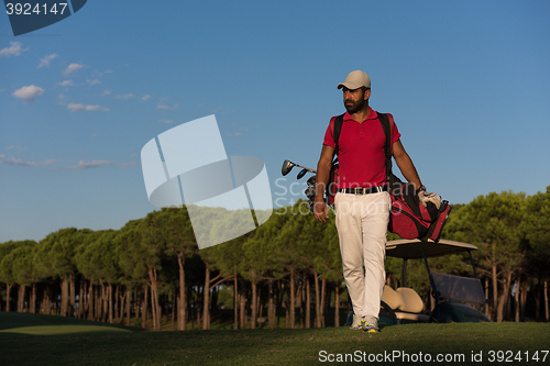 Image of golfer  walking and carrying golf  bag