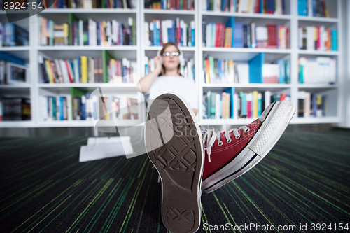 Image of female student study in library, using tablet and searching for 