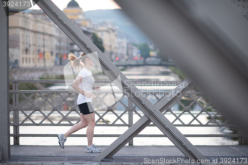Image of sporty woman running  on sidewalk