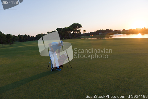 Image of golfer  walking and carrying golf  bag at beautiful sunset