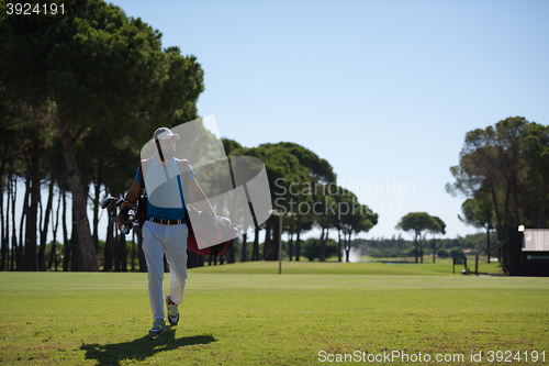 Image of golf player walking and carrying bag