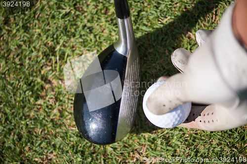 Image of golf player placing ball on tee