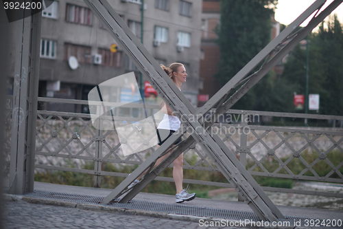 Image of sporty woman running  on sidewalk