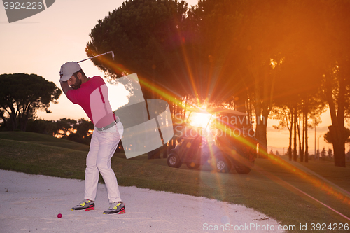 Image of golfer hitting a sand bunker shot on sunset