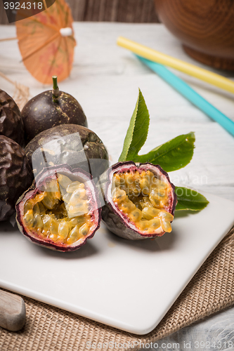 Image of Passion fruits on white ceramic tray on wooden table background.