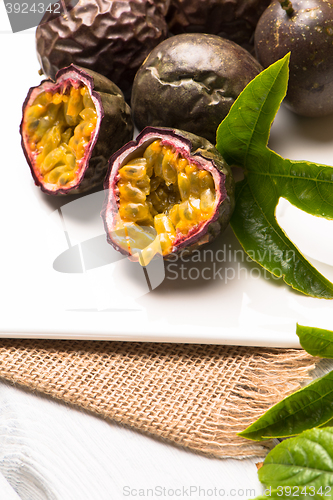 Image of Passion fruits on white ceramic tray on wooden table background.