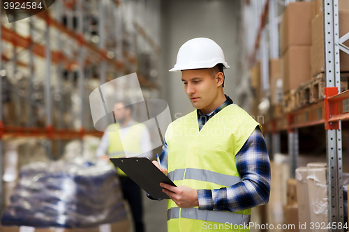 Image of man with clipboard in safety vest at warehouse