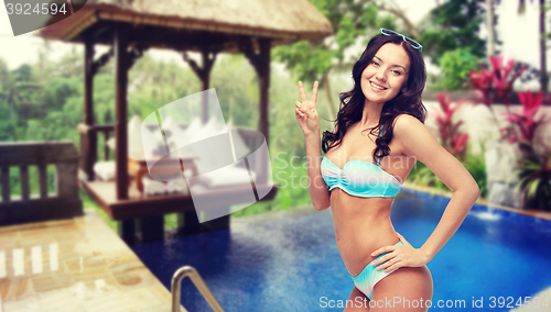 Image of happy woman in swimsuit showing victory hand sign