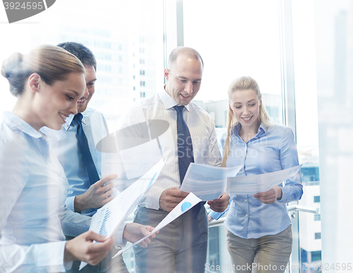 Image of smiling businesspeople with papers in office