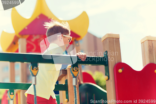 Image of happy little boy climbing on children playground