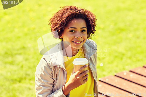 Image of smiling african woman drinking coffee outdoors 