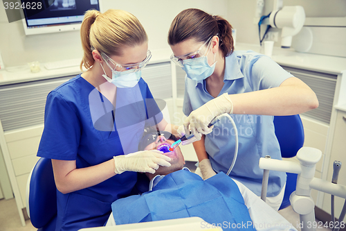 Image of dentists treating male patient teeth at clinic