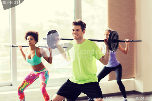 Image of group of people exercising with barbell in gym