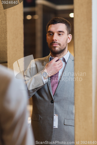 Image of man trying jacket on at mirror in clothing store