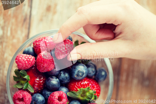 Image of close up of woman hands with berries in glass bowl