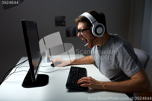 Image of man in headset playing computer video game at home