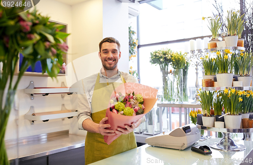 Image of smiling florist man making bunch at flower shop