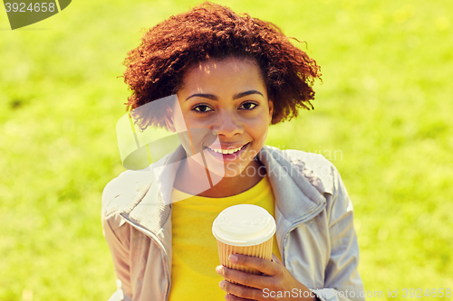 Image of smiling african woman drinking coffee outdoors 