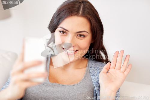 Image of happy young woman with smartphone at home