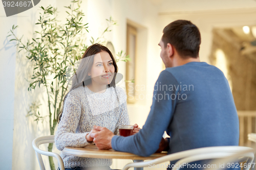 Image of happy couple with tea holding hands at restaurant